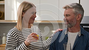 Happy couple family Caucasian adult woman and mature man middle-aged husband and wife drinking orange juice in home