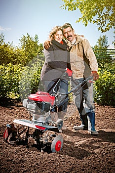 Happy couple of a family of farmers on their garden rejoice on a plant