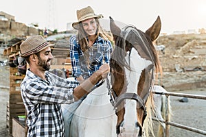 Happy couple of farmers having fun with horse inside ranch