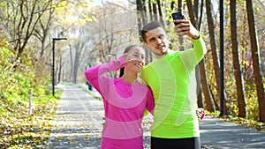 Happy couple of fitness bloggers recording video in autumn park