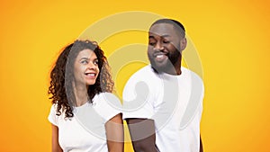 Happy couple flirting and smiling each other on yellow background, acquaintance