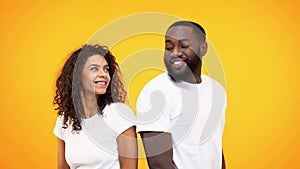 Happy couple flirting and smiling each other on yellow background, acquaintance photo