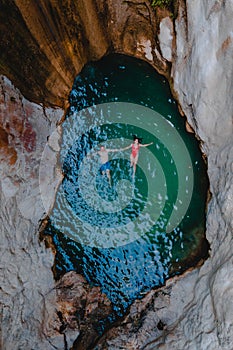 happy couple floating in waterfall lake overhead top view