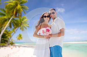 Happy couple with flowers over tropical beach