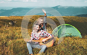 Happy couple friends camping, and playing guitar together in summer at nature forest. Couple in love on camp.