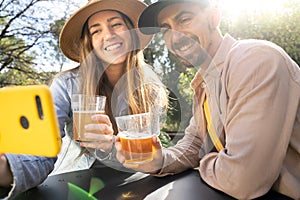 Happy couple friends have drinks and taking selfie photo in a backyard on sunny day toast together.