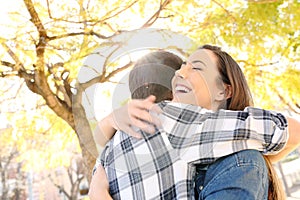 Happy couple or friends hugging in a park