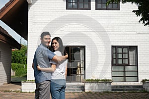 Happy couple in front of the New Home On Moving In Day, and start a new life family. Concept of homeowner and relocation