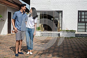 Happy couple in front of the New Home On Moving In Day, and start a new life family. Concept of homeowner and relocation