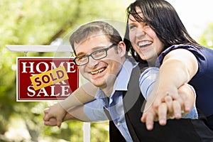 Happy Couple in Front of Sold Real Estate Sign