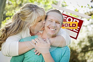 Happy Couple In Front Sold Real Estate Sign