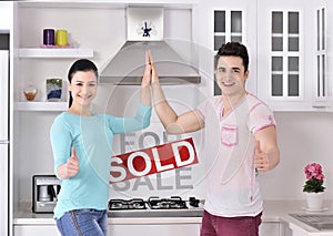 Happy Couple in Front of Sold Real Estate Sign