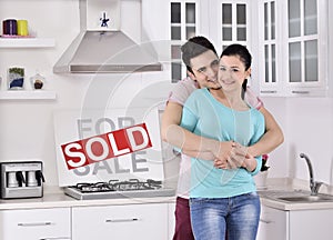 Happy Couple in Front of Sold Real Estate Sign