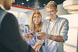 Happy couple getting a car key from stylish sale manager