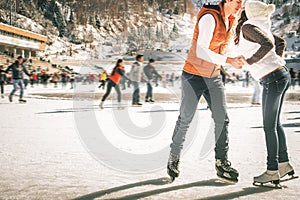 Happy couple, girls and boy ice skating outdoor at rink