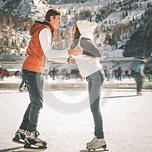 Happy couple, girls and boy ice skating outdoor at rink