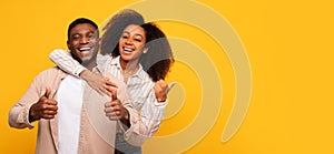 Happy couple giving thumbs up on yellow background