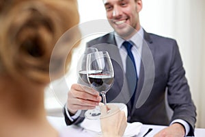 Happy couple with glasses of wine at restaurant