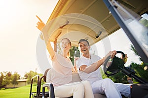 Happy couple on a golf cart rides to play golf