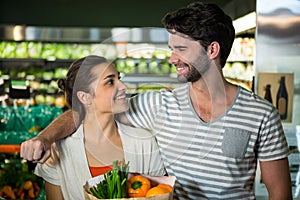 Happy couple with a grocery bag smiling at each other in organic section