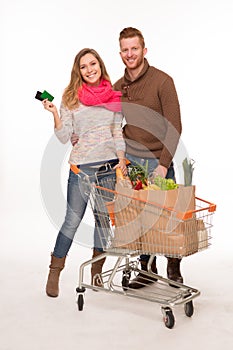 Happy couple with grocery shopping bags in shopping cart