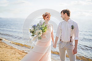 The happy couple groom and bride with wedding bouquet are on the beach