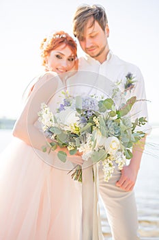 The happy couple groom and bride with wedding bouquet are on the beach