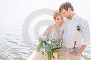 The happy couple groom and bride with wedding bouquet are on the beach