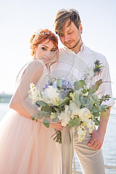 The happy couple groom and bride with wedding bouquet are on the beach