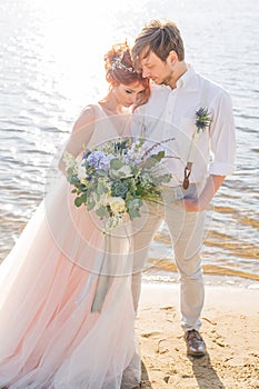 The happy couple groom and bride with wedding bouquet are on the beach