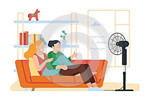 Happy couple guy and girl chill under electric fan at home in summer heat. Man and woman sitting on sofa. Air