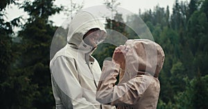 A happy couple, a guy and a girl, rejoice and hug during the rain against the backdrop of a mountain forest