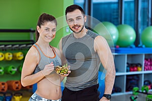 Happy couple in gym feeding each other with fresh salad