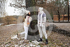 Happy couple have a fun in winter forest. Tangerine mood in winter holidays. Emotional young couple in white sweater having fun