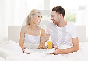 Happy couple having breakfast in bed at home