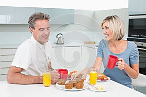 Happy couple having breakfast in kitchen