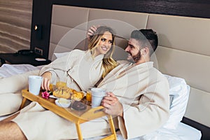 Happy couple having breakfast in luxury hotel room