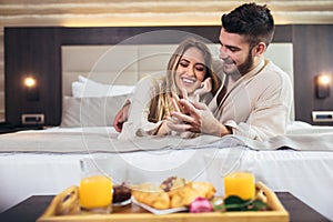 Happy couple having breakfast in luxury hotel room