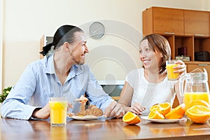 Happy couple having breakfast with oranges juice