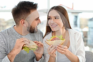Happy couple having breakfast with sandwiches at home