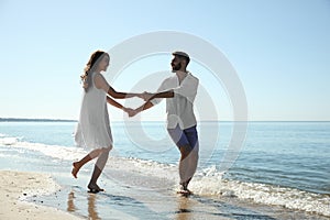 Happy couple having fun on beach near sea. Honeymoon trip