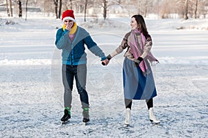 Happy couple having fun ice skating on rink outdoors