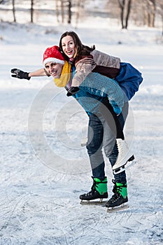 Happy couple having fun ice skating on rink outdoors.