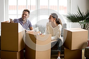 Happy couple having fun laughing unpacking boxes on moving day
