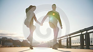 Happy couple having fun outdoors - male and woman are dancing at sunset, slow-motion