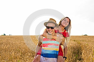 Happy Couple Having Fun Outdoors on wheat field. Freedom Concept. Piggyback