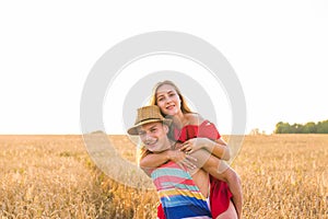 Happy Couple Having Fun Outdoors on wheat field. Laughing Joyful Family together. Freedom Concept. Piggyback