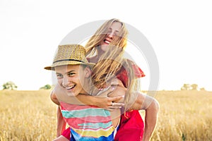 Happy Couple Having Fun Outdoors on wheat field over sunset. Laughing Joyful Family together. Freedom Concept. Piggyback