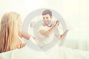 Happy couple having pillow fight in bed at home