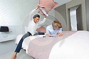 happy couple having pillow fight in hotel room